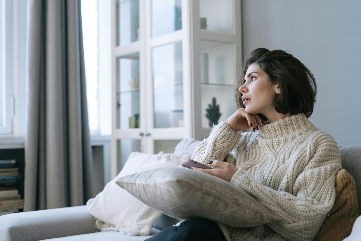 Personne angoissée le dimanche soir tenant une tasse de thé, regardant par la fenêtre